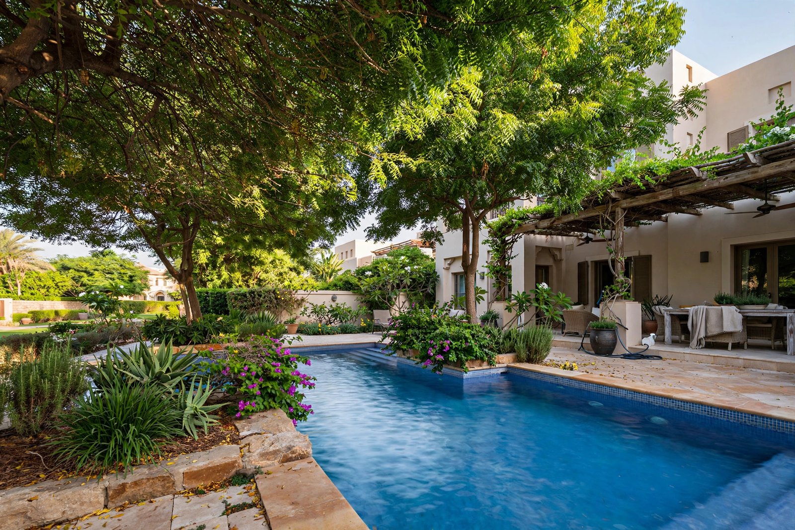 Pool cleaning and poolside landscaping in The Meadows, Dubai – pool shaded by mature trees